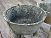 An old, gray stone composite bucket with a textured surface, likely dating back to the 1950s, displayed on a wooden surface.