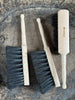 Three brushes with wooden handles on a stone surface