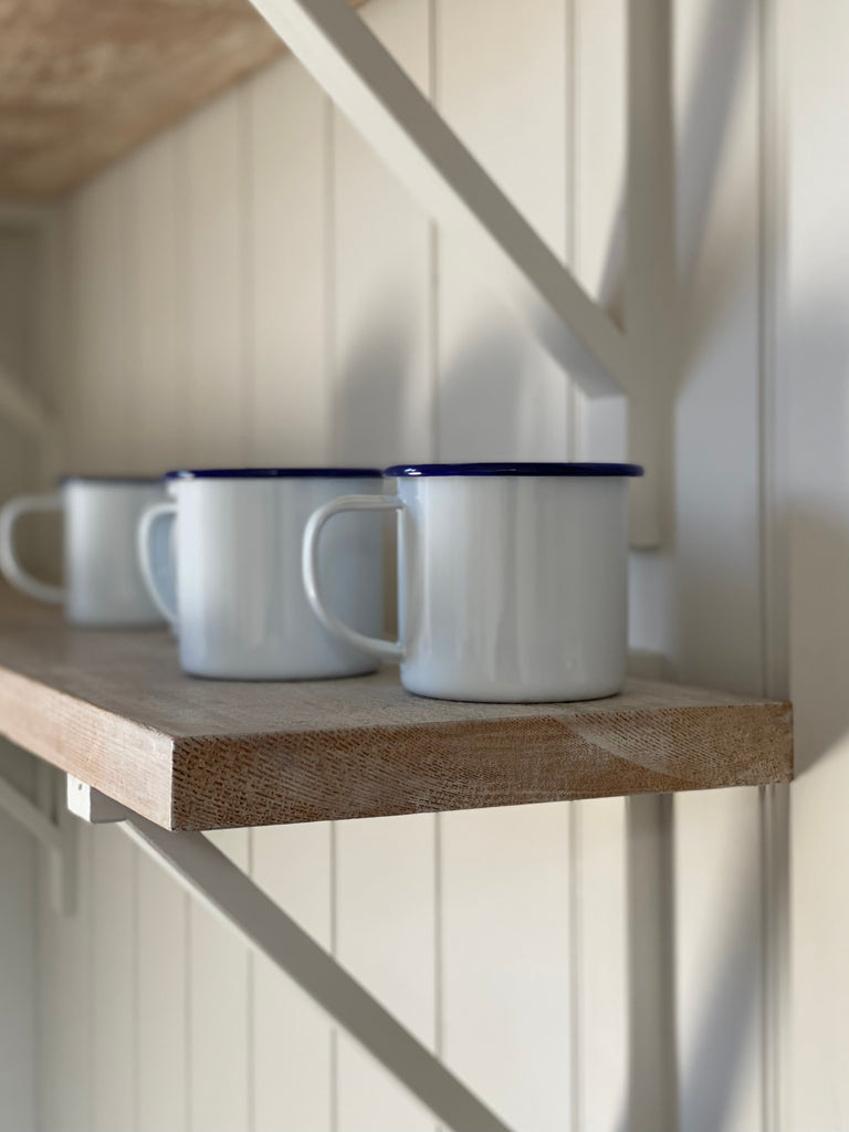 white enamel mug with a dark blue rim. 