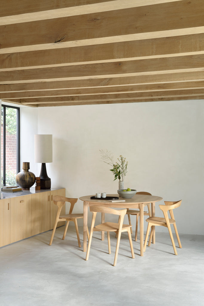 amelie round extendable table surrounded by oak amelie chairs. the table extends into an oval shape. The table is a light natural oak colour,