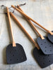 Black leather paddle, wooden oiled beech handle with hanging loop.
