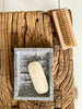 Matte, unpolished grey granite soap dish with recessed centre and ridges for soap.