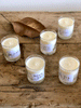 Votive candles in clear glass with a white printed label.