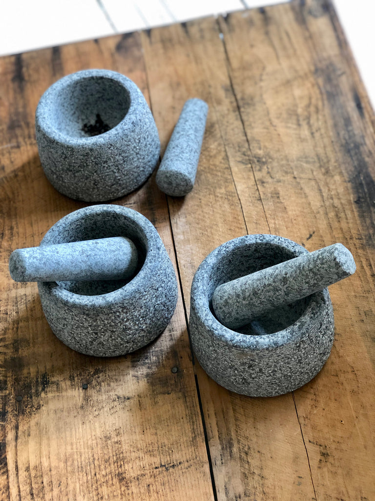 unpolished grey granite pestle and mortar, pictured crushing spices.